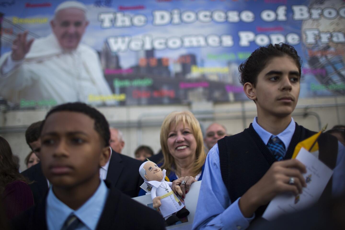 A woman holds a doll of Pope Francis while people attend the departure of the Pope from John F. Kennedy International Airport in New York Sept. 26, 2015.