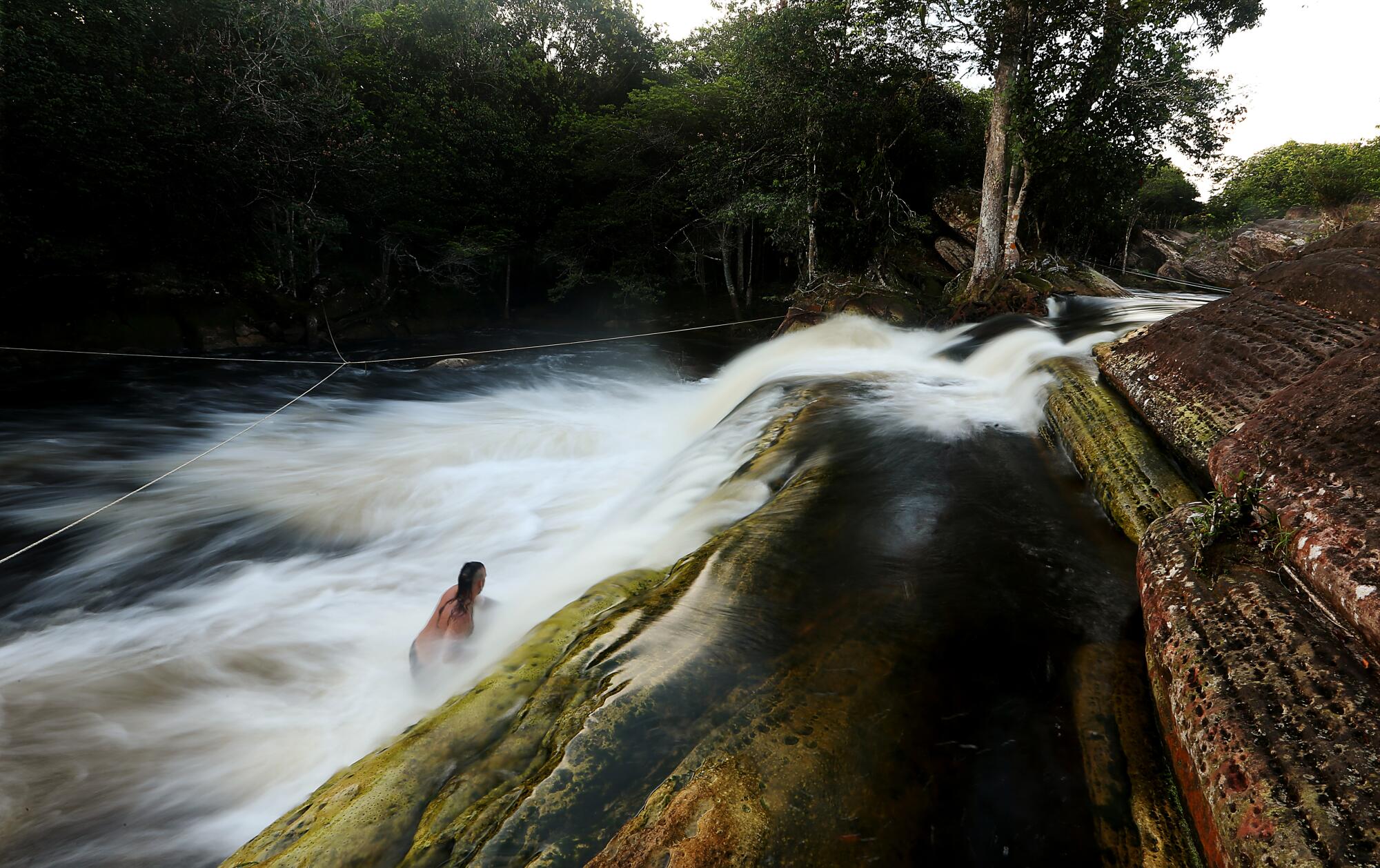 A man wades into falls of a stream 