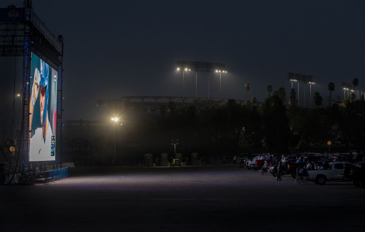 Cars are parked in front of a giant screen at Dodger Stadium