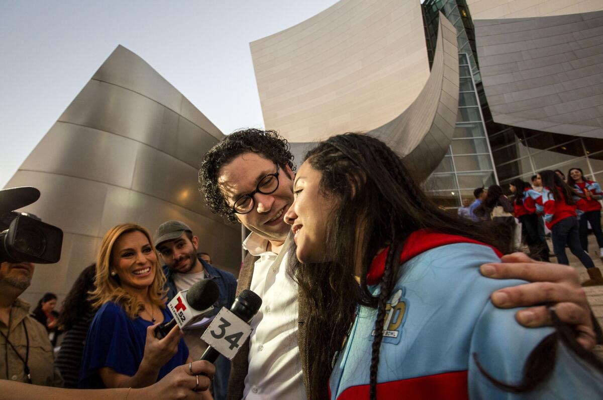 Los Angeles Philharmonic's Gustavo Dudamel and YOLA cellist Karla Melgar are interviewed by TV reporters outside Disney Hall in downtown L.A.