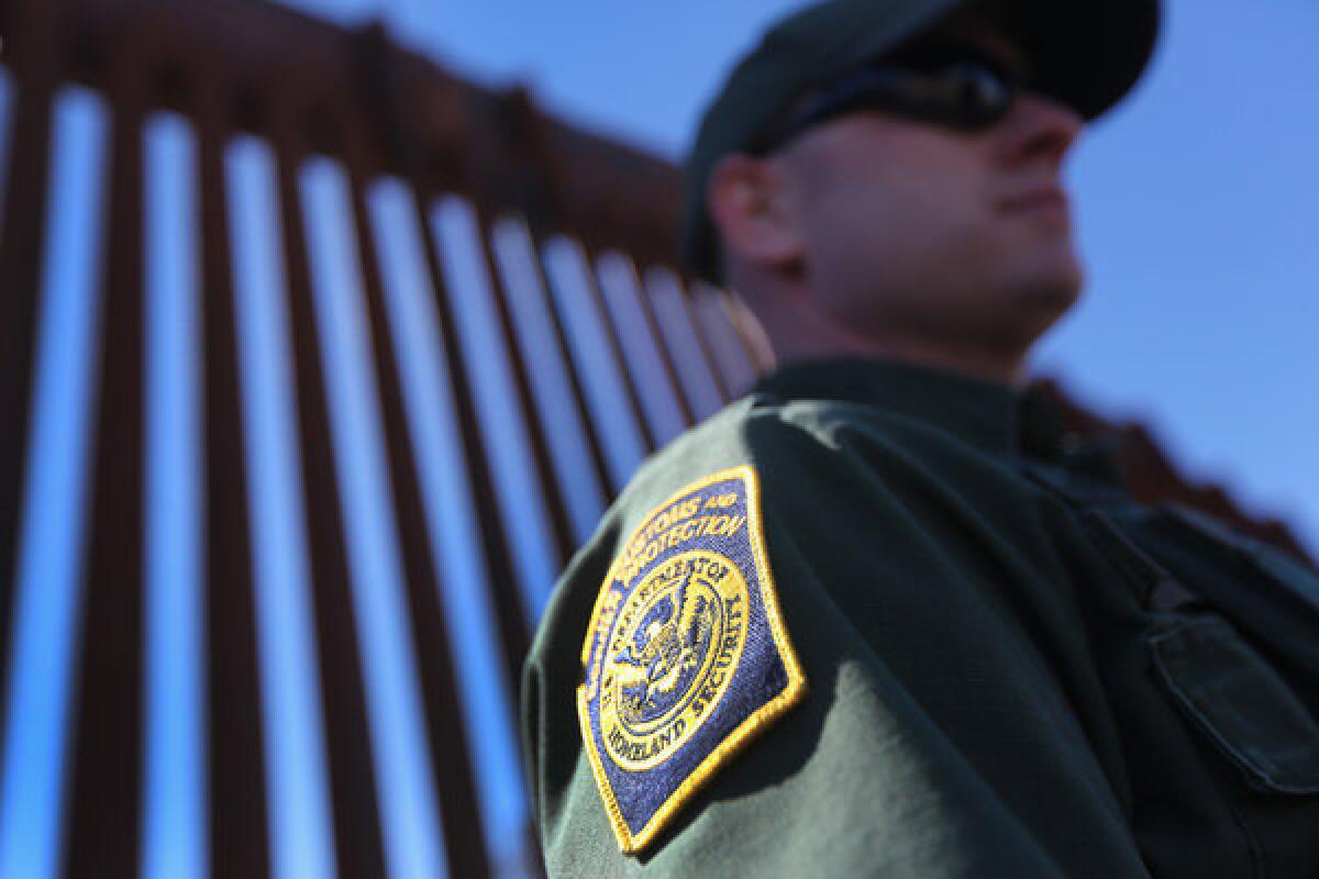 A U.S. Border Patrol agent stands guard at the U.S.-Mexico fence in Nogales, Ariz.