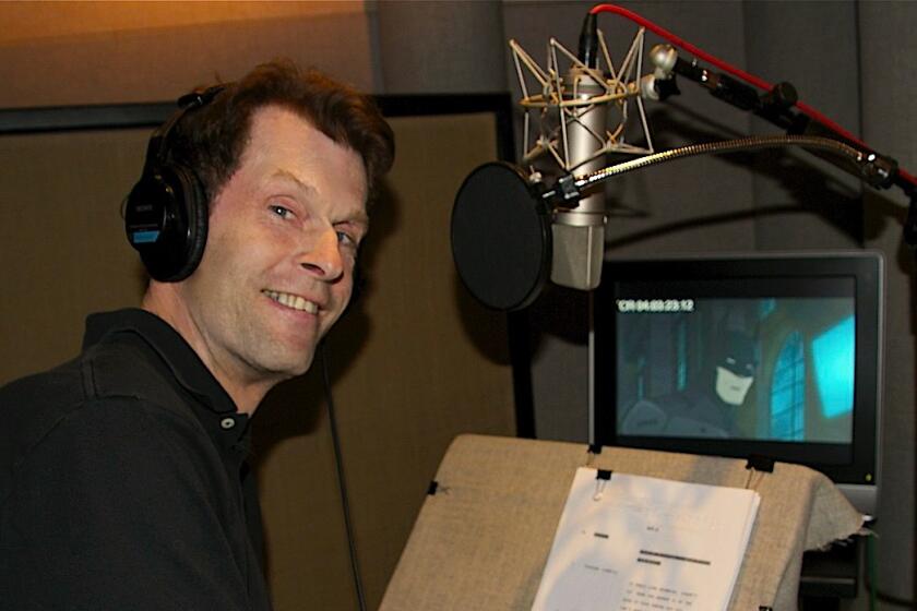 Kevin Conroy, the voice of Batman, sits in a voiceover booth