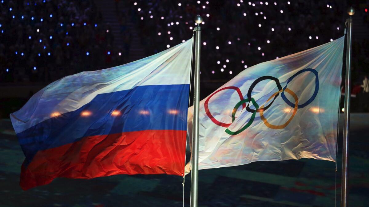 The Russian and Olympic flags fly during the closing ceremony of the Sochi 2014 Olympic Games.