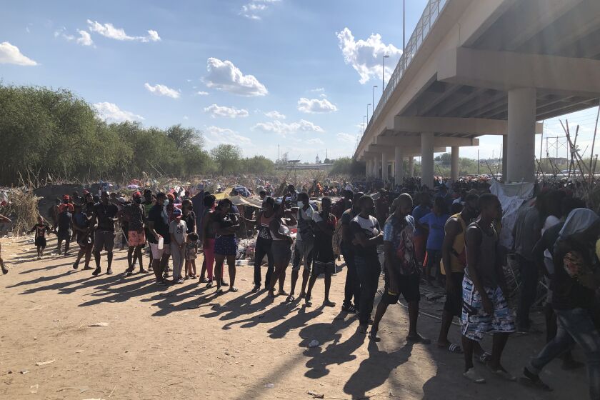 Migrants waiting in line for food Sunday at the camp near the border bridge in Del Rio, Texas.