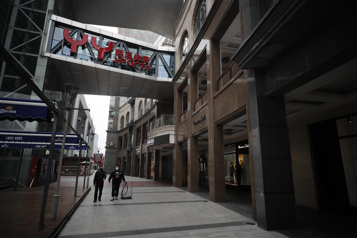 Trabajadores con máscaras sanitarias en un centro comercial vacío en Beijing, el 24 de febrero del 2020. (AP Photo/Andy Wong)