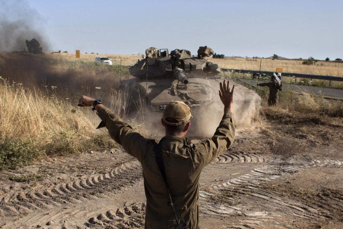 An Israeli soldier directs a tank near the Quneitra crossing with Syria.