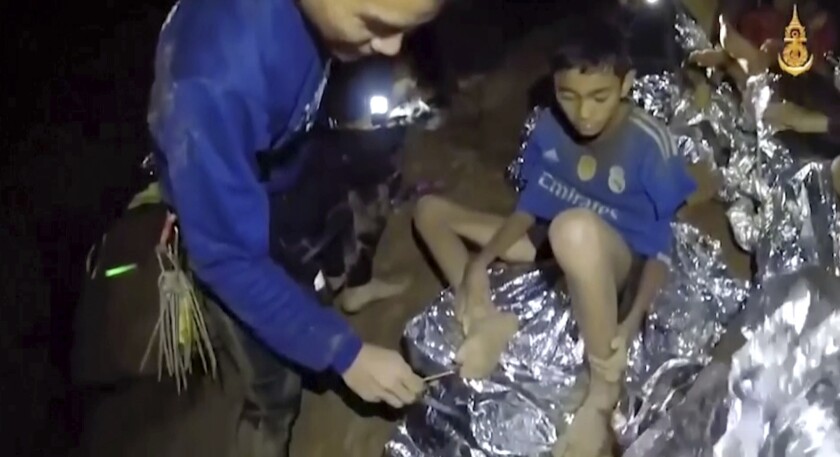 In this image taken from video provided by the Royal Thai Navy Facebook Page, a Thai Navy SEAL medic helps an injured child inside a cave in Mae Sai, northern Thailand, on Tuesday.