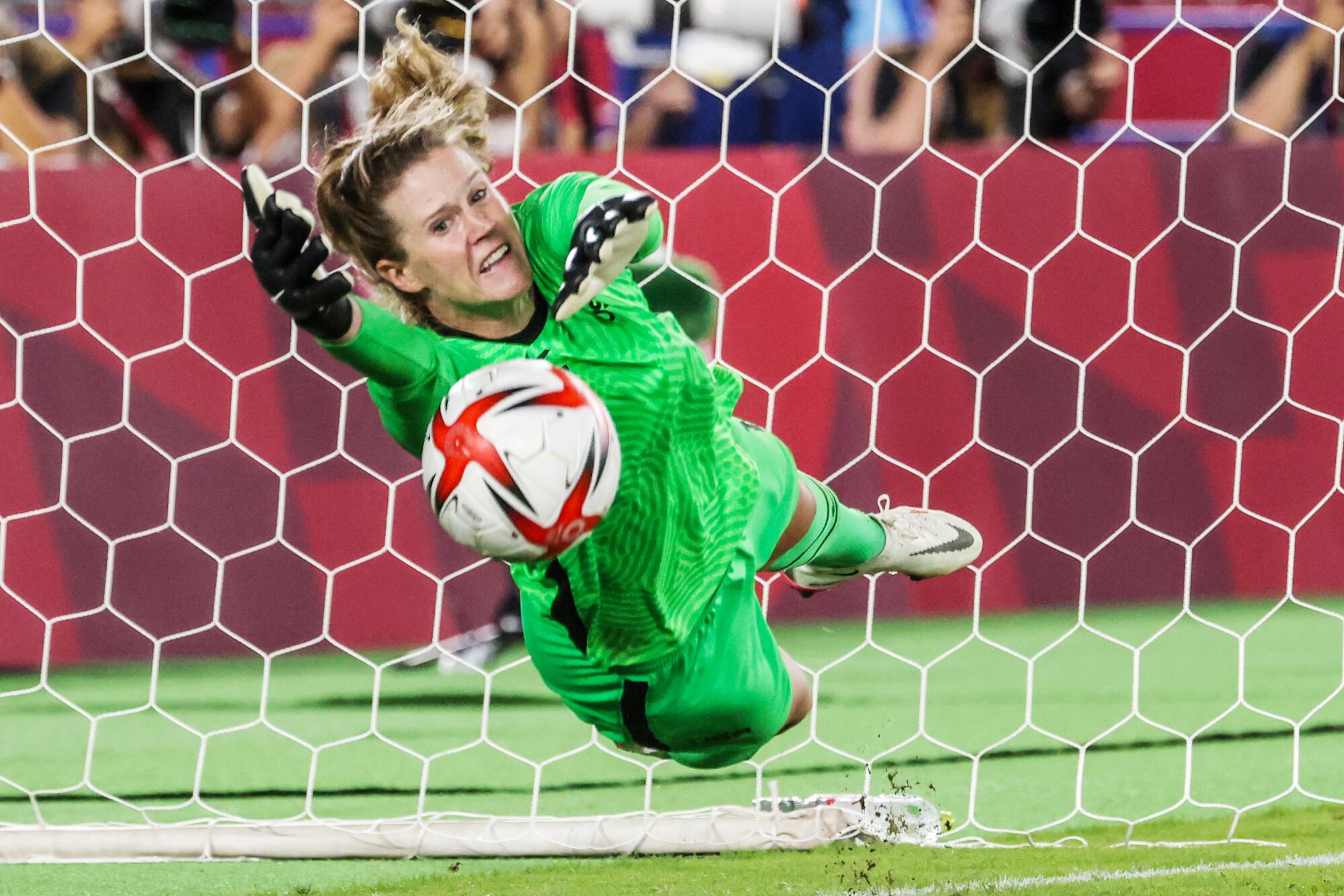 USA goalkeeper Alyssa Naeher lunges to make a save in front of the net.
