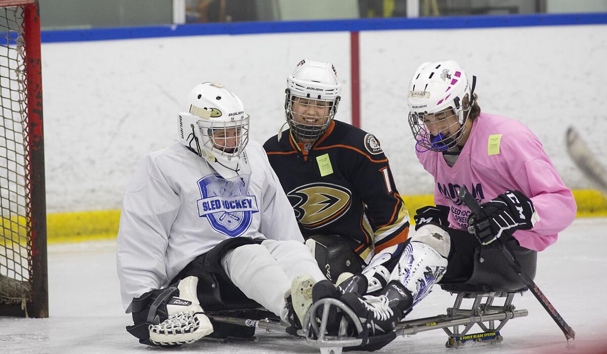 Lera Doederlein, center, smiles while participating in sled hockey practice with her San Diego Ducks teammates Parker Olenick, left, and Zachary Grover.