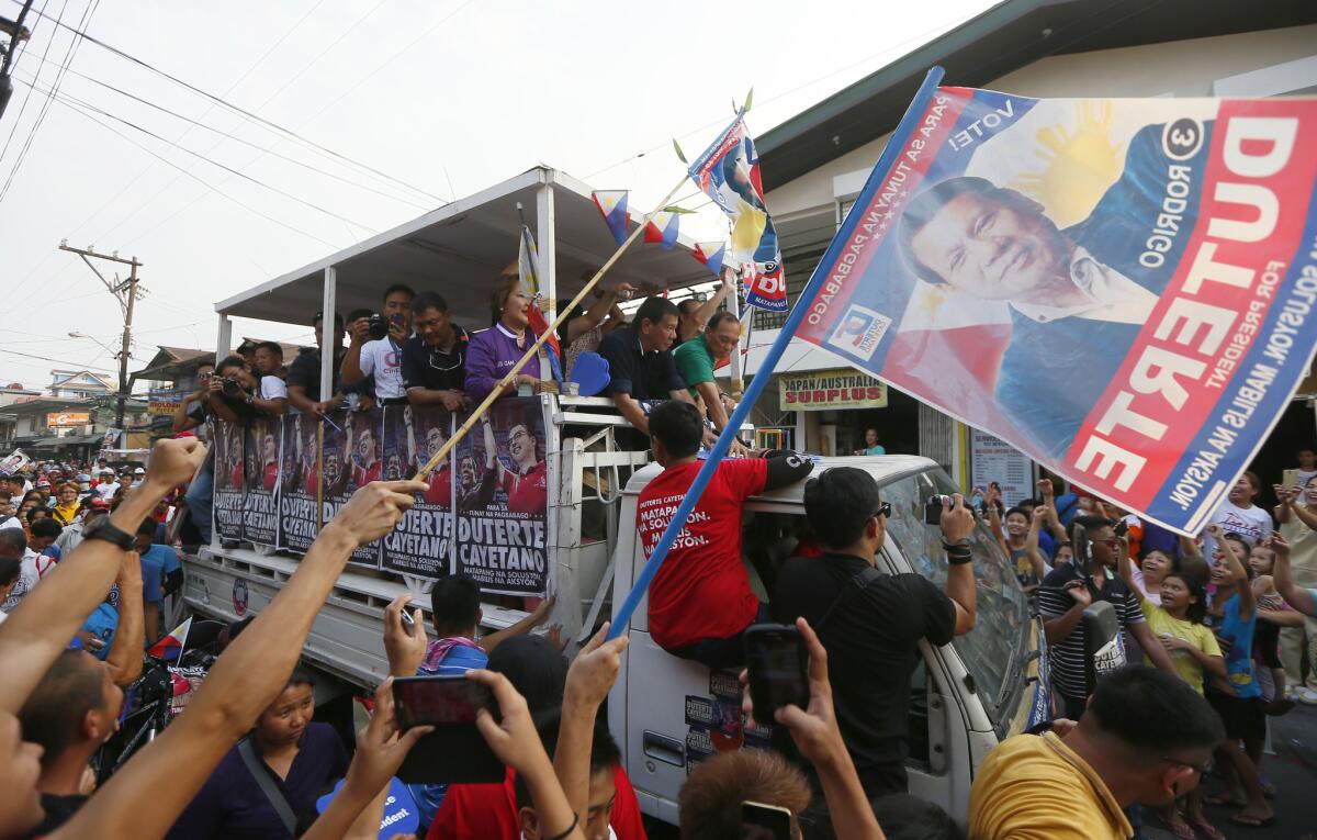 Supporters cheer Duterte, center in black shirt, as his campaign motorcade makes its way through the streets of Malabon.