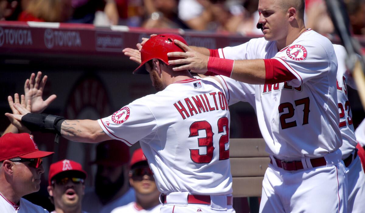 Angels left fielder Josh Hamilton (32) has his helmet taken off by teammate Mike Trout (27) after returning to the dugout following Erick Aybar's run-scoring single against the A's in the second inning Sunday.