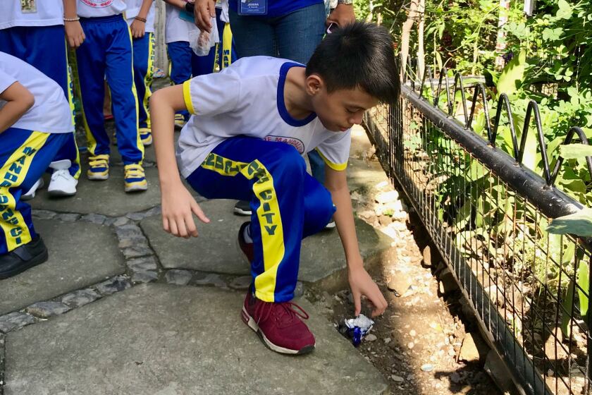 Elementary school students collect litter from along Maytunas Creek, a tributary of the heavily polluted Pasig River in Manila, Philippines.