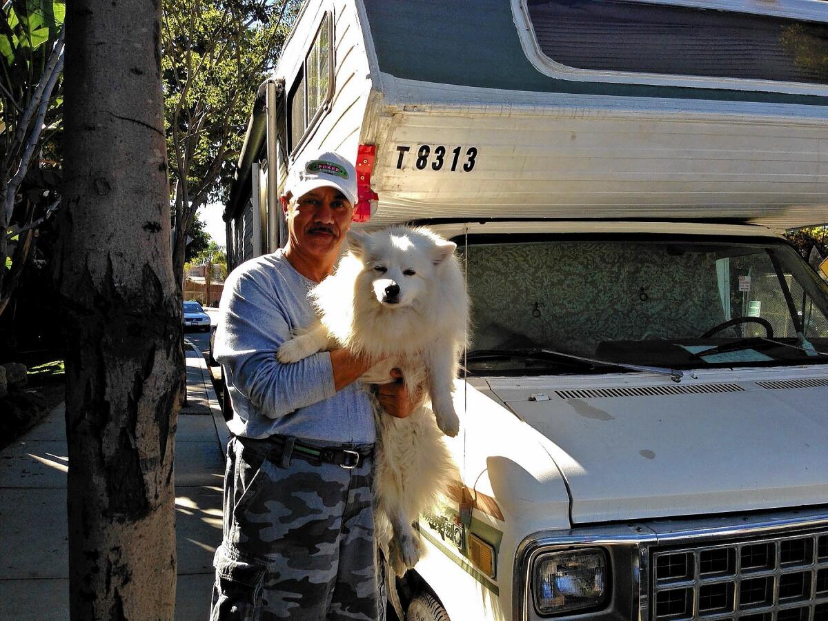 Farhad Alexander-Alizadeh, 57, with his American Eskimo dog, outside the RV he lives in parked on a Brentwood street.