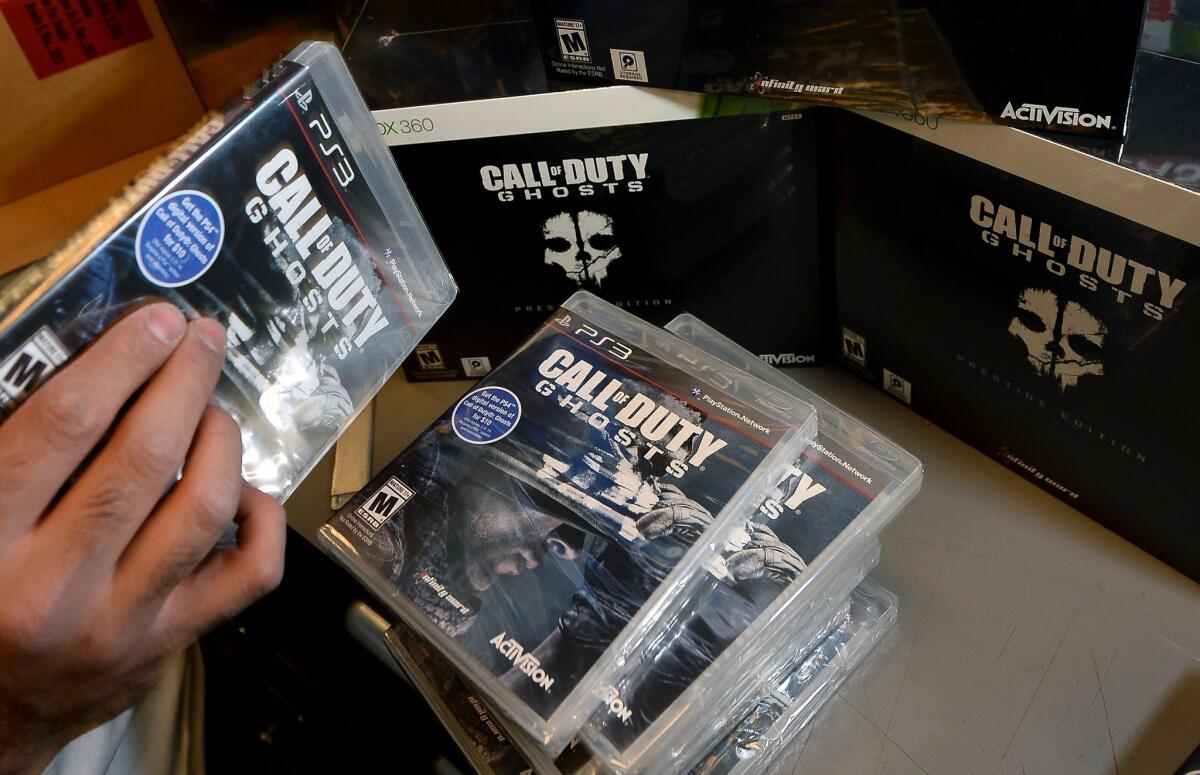 A store manager stacks copies of "Call of Duty: Ghosts" during a launch event for the highly anticipated video game at a GameStop store.