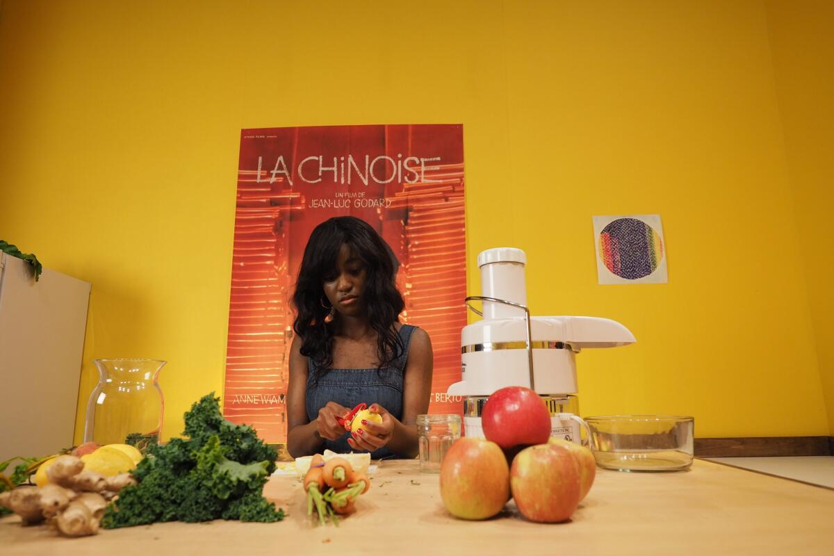 In "The Inheritance," Aurielle Akerele prepares fruit and vegetables. Behind her: a poster of Godard's "La Chinoise."