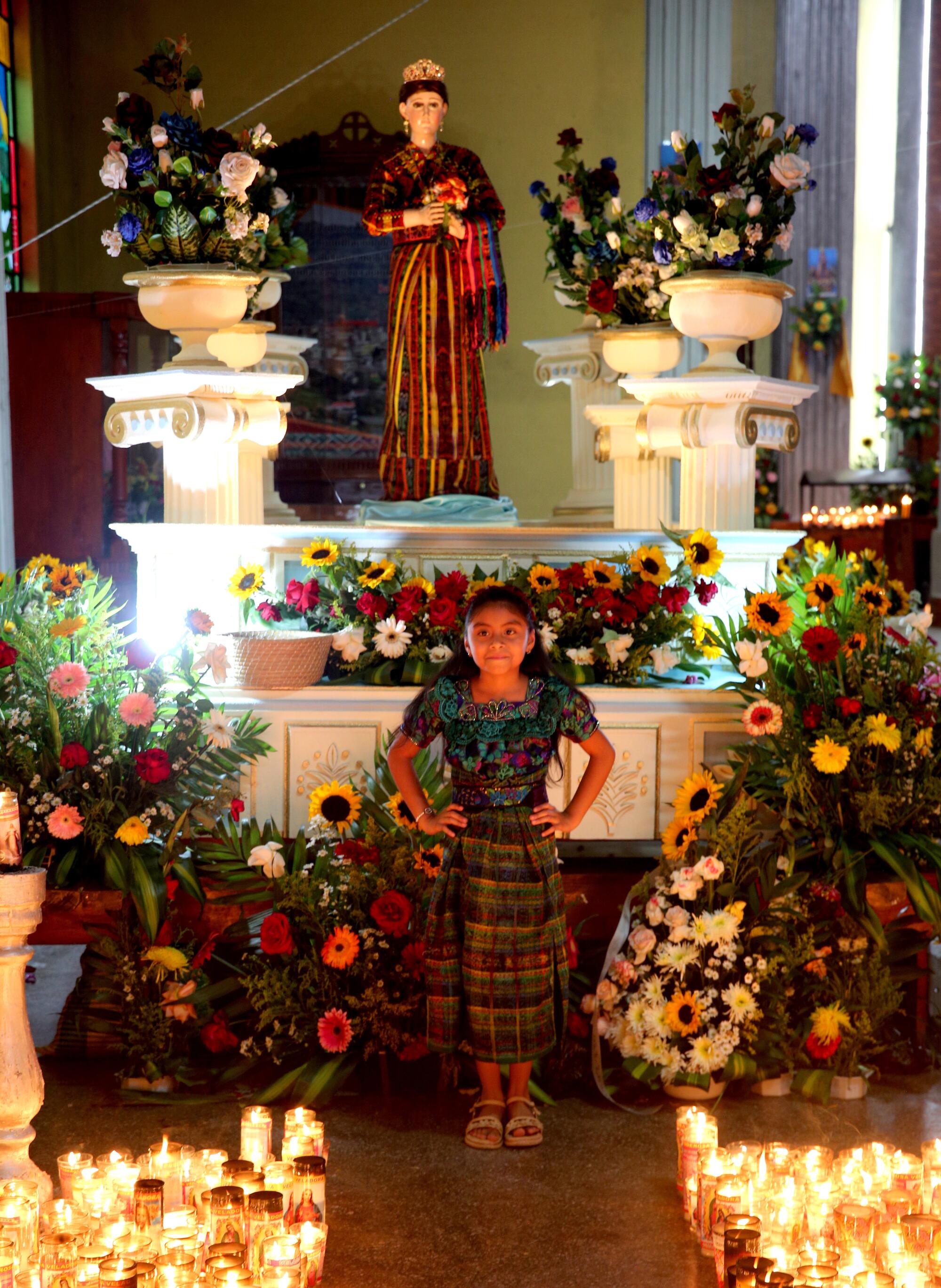 Marleni Cardonas Miranda poses for a photo in front of a statue of the Santa Virgen, inside the Iglesia Catolica