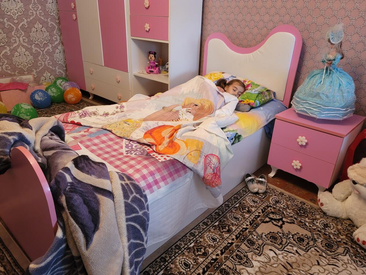 Three-year-old Khadija, who lost her parents and sister in a missile strike on Ganja, Azerbaijan, lies in her bed.