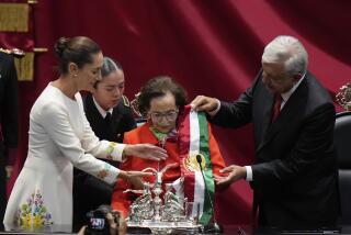 Outgoing President Andres Manuel Lopez Obrador hands over the presidential sash to Ifigenia Martinez, president of the Chamber of Deputies, during the swearing-in ceremony of Claudia Sheinbaum, left, at Congress in Mexico City, Tuesday, Oct. 1, 2024. (AP Photo/Eduardo Verdugo)