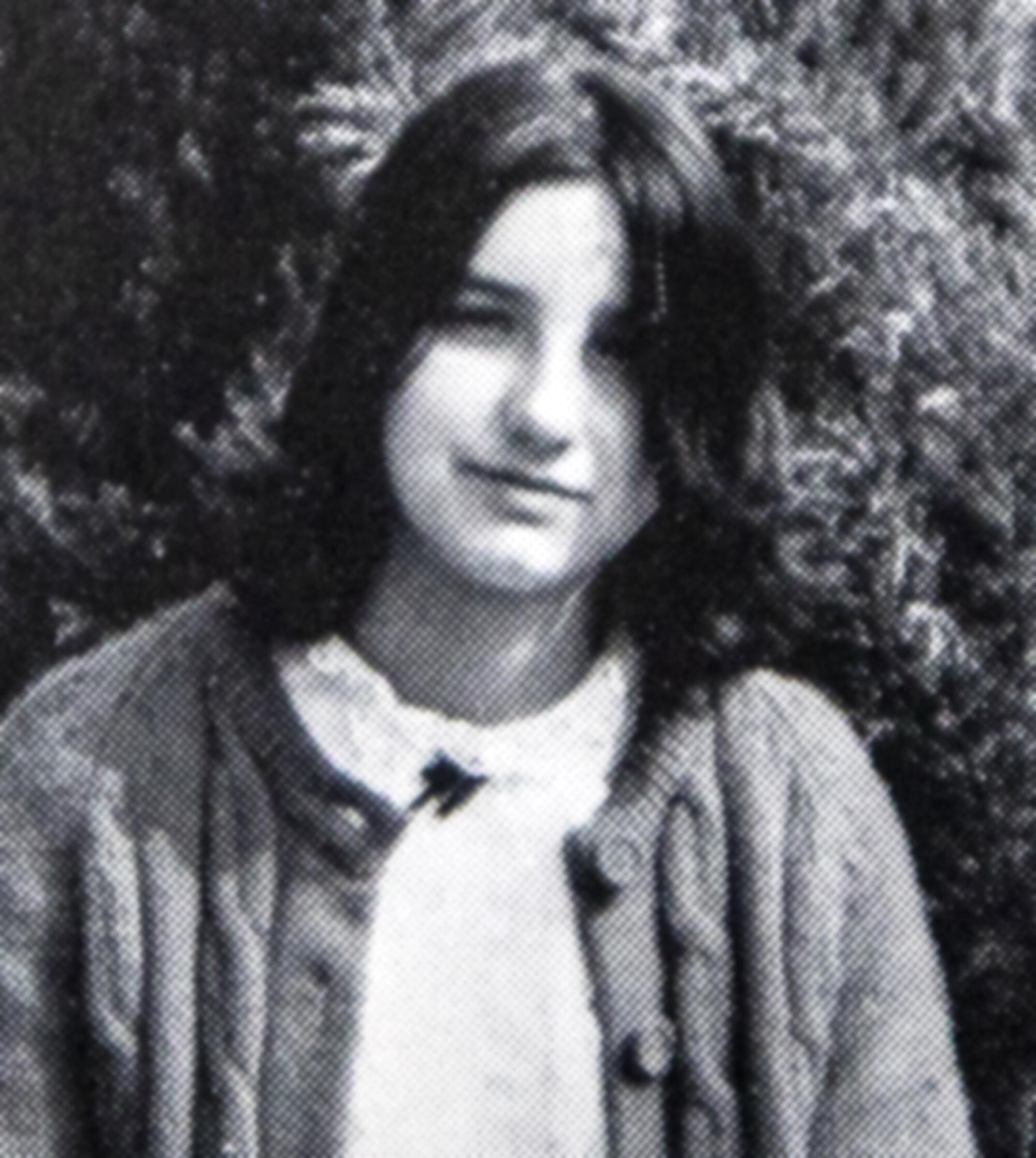 A black-and-white photo shows a girl with dark, shoulder-length hair. She is smiling slightly and wearing a cardigan sweater