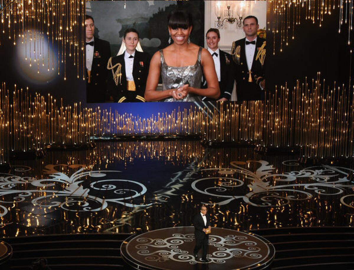 First Lady Michelle Obama, on a video screen via satellite, announces the best picture Oscar with Jack Nicholson, who was at the Dolby Theatre.