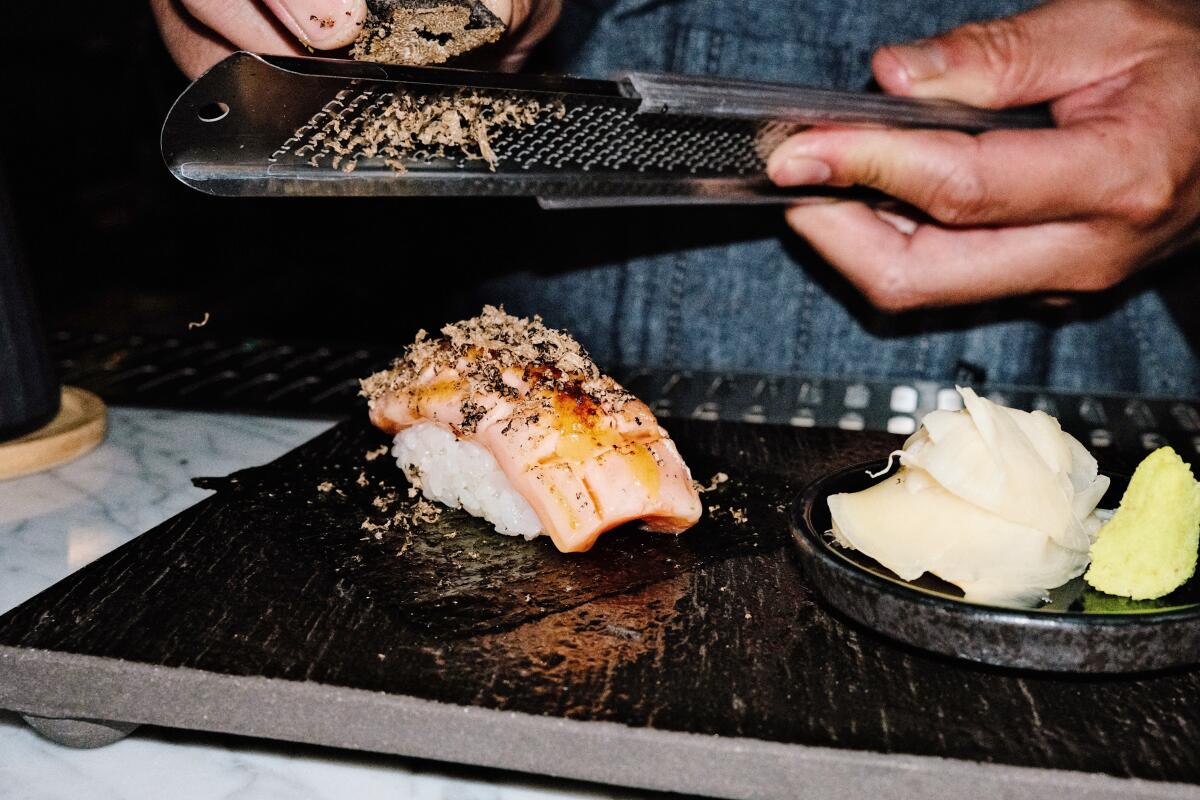 A hand shaves black truffle onto salmon and rice at Iki Nori sushi bar in Hollywood.