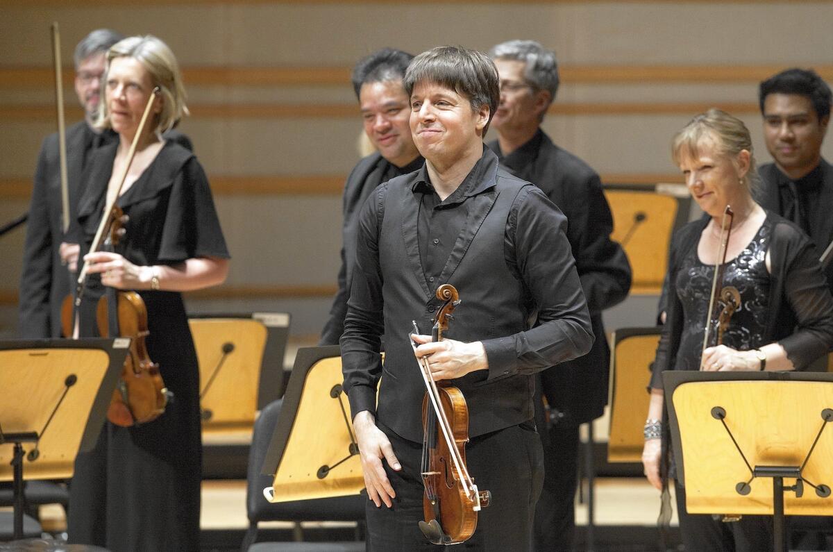 Violinist and conductor Joshua Bell stands with members of the Academy of St. Martin in the Fields on Monday during their performance in the Renee and Henry Segerstrom Concert Hall in Costa Mesa.