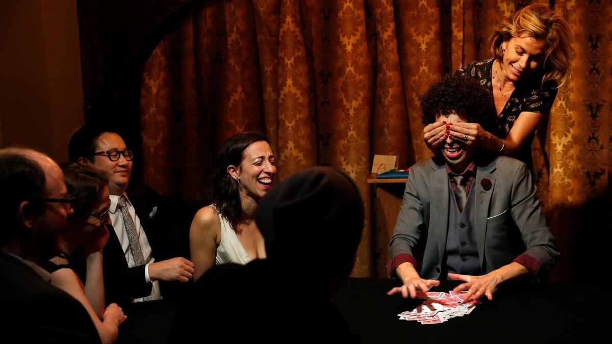 Diane Scheiner, right, covers the eyes of sleight-of-hand magician Siegfried Tieber as he performs a card trick during his magic show "See/Saw."