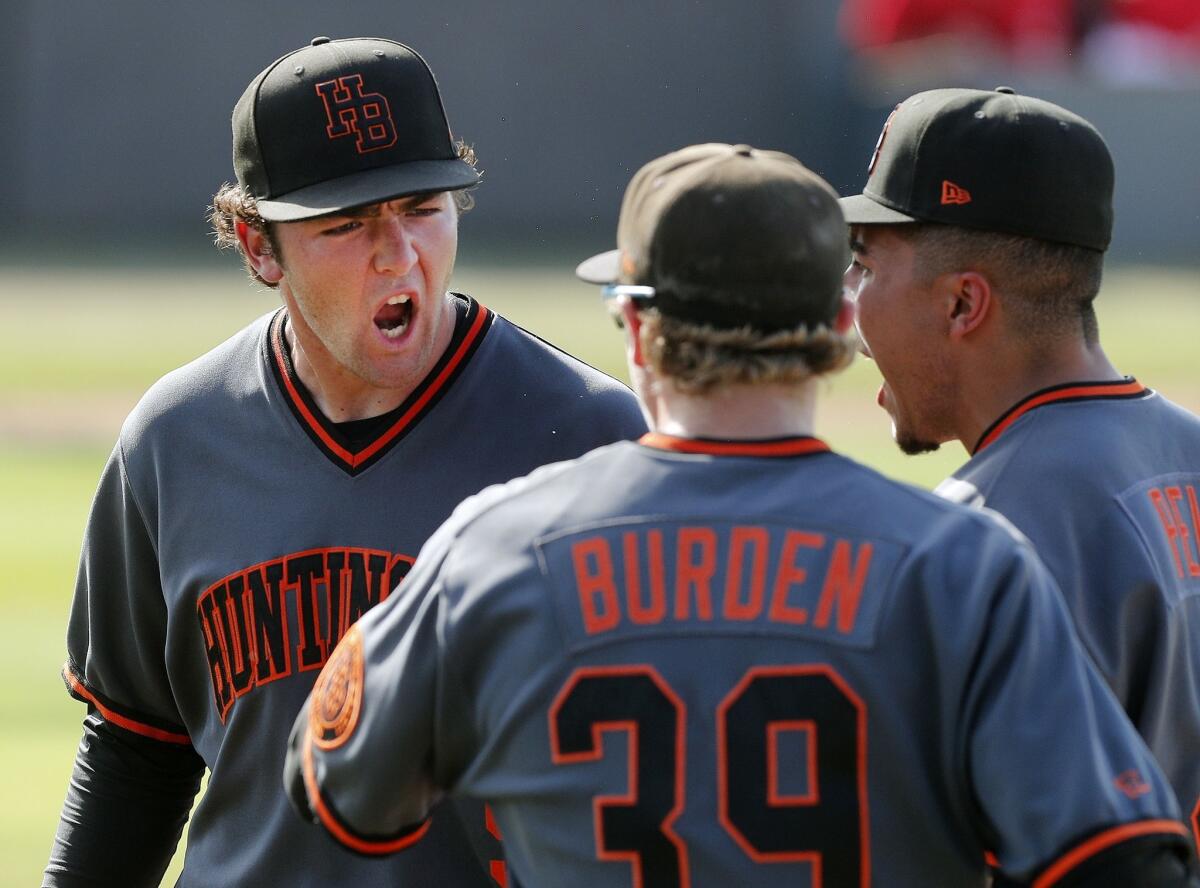 Huntington Beach High's Josh Hahn, left, yells, "Lets Go!" to teammates Jag Burden, center, and Edward Pelc after getting out of a jam in the fourth inning against Studio City Harvard-Westlake in a CIF Southern Section Division 1 semifinal playoff game on Tuesday.