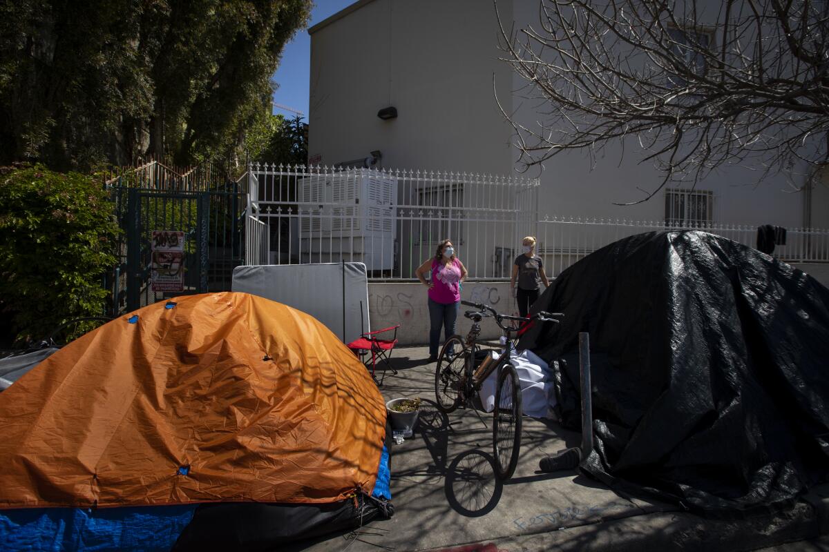 Dr. Susan Partovi, left, and Heidi Roth look at a homeless encampment on a sidewalk in Los Angeles.