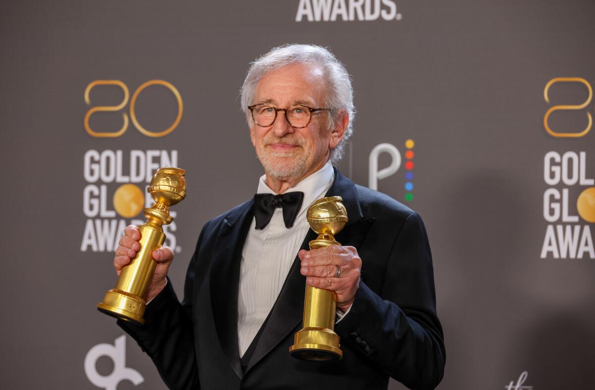 Steven Spielberg wearing a tuxedo and holding two Golden Globe Awards