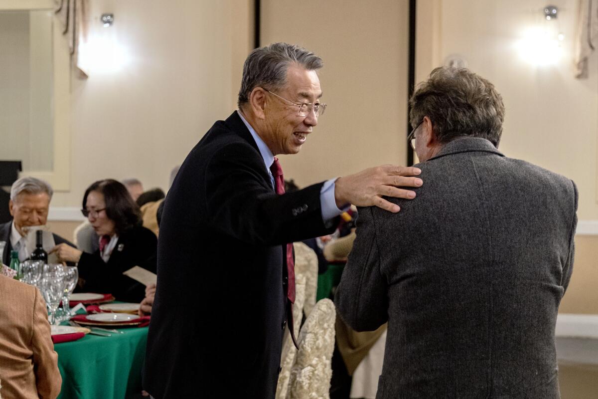 Peter YS Kim, left, greets a guest during their end-of-year alumni gathering.