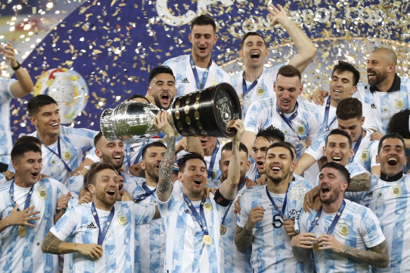 Argentina's Lionel Messi holds the trophy as he celebrates with teammates