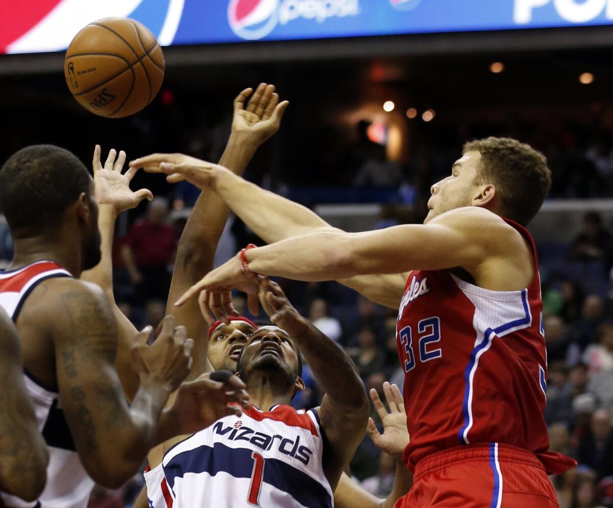 Washington forward Trevor Ariza, wearing No. 1, tries to shoot between Clippers forwards Jared Dudley, left, and Blake Griffin on Saturday night.