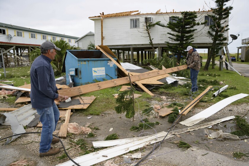 FILE - In this Friday, Oct. 30, 2020, file photo, Mark Andollina, left, and Shane Holder, remove part of a roof damaged by Hurricane Zeta from the road at the Cajun Tide Beach Resort in Grand Isle, La. The late-hitting Hurricane Zeta has been upgraded to a major, Category 3 storm, according to a report by the National Hurricane Center released Tuesday, May 11, 2021. (AP Photo/Matthew Hinton, File)