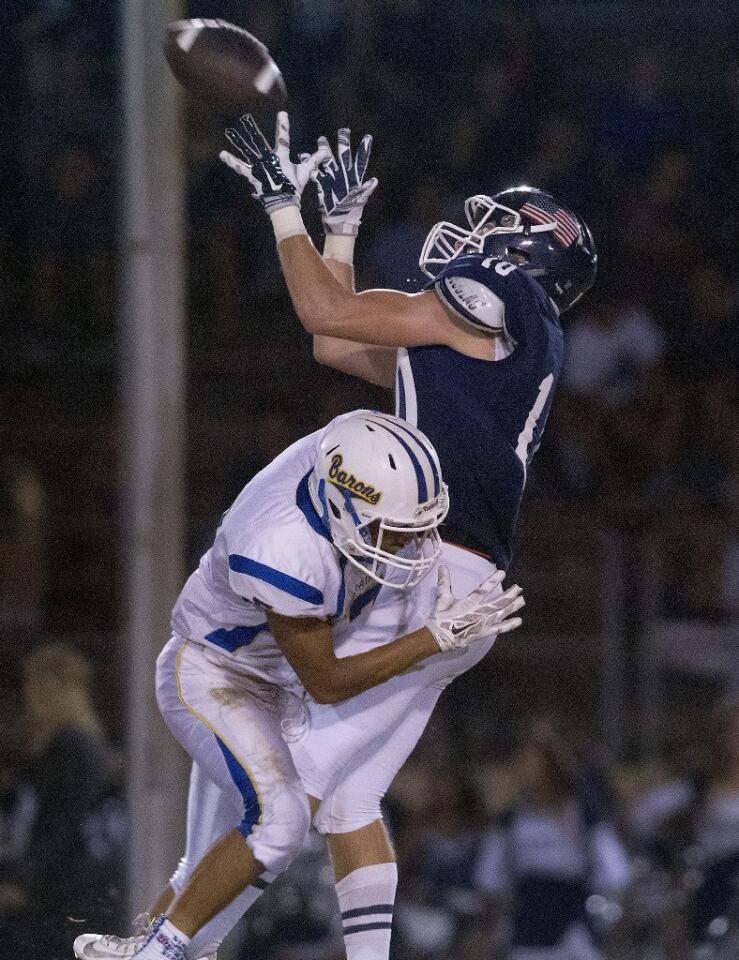 Newport Harbor High's Reed Rutter is unable to secure a pass as he's taken down by a Fountain Valley defender during the first half against in a Sunset League season opener at Davidson Field on Thursday.