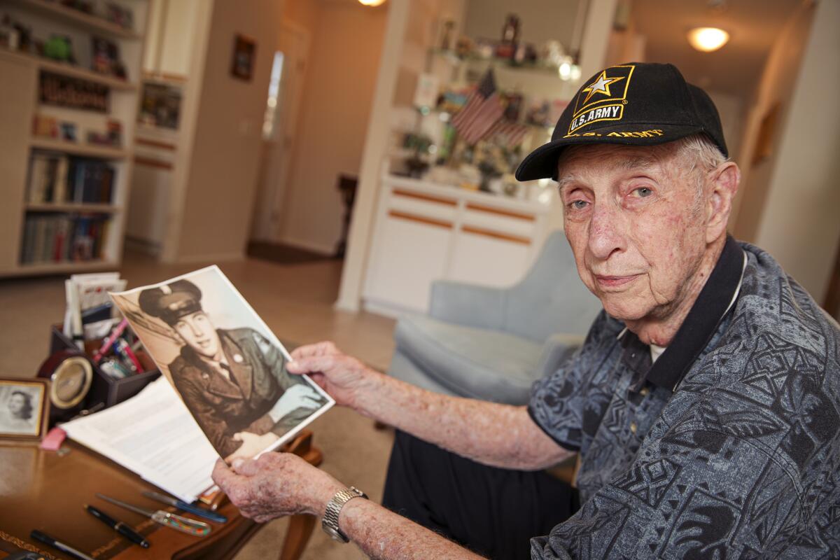 An 88-year-old Army veteran shows an old photo.
