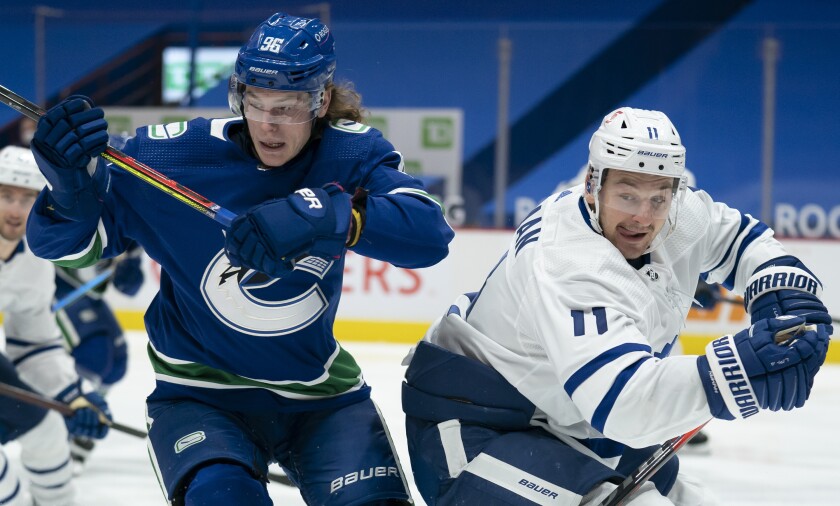 Vancouver Canucks center Adam Gaudette (96) works against Toronto Maple Leafs left wing Zach Hyman (11) during the second period of an NHL hockey game Thursday, March 4, 2021, in Vancouver, British Columbia. (Jonathan Hayward/The Canadian Press via AP)