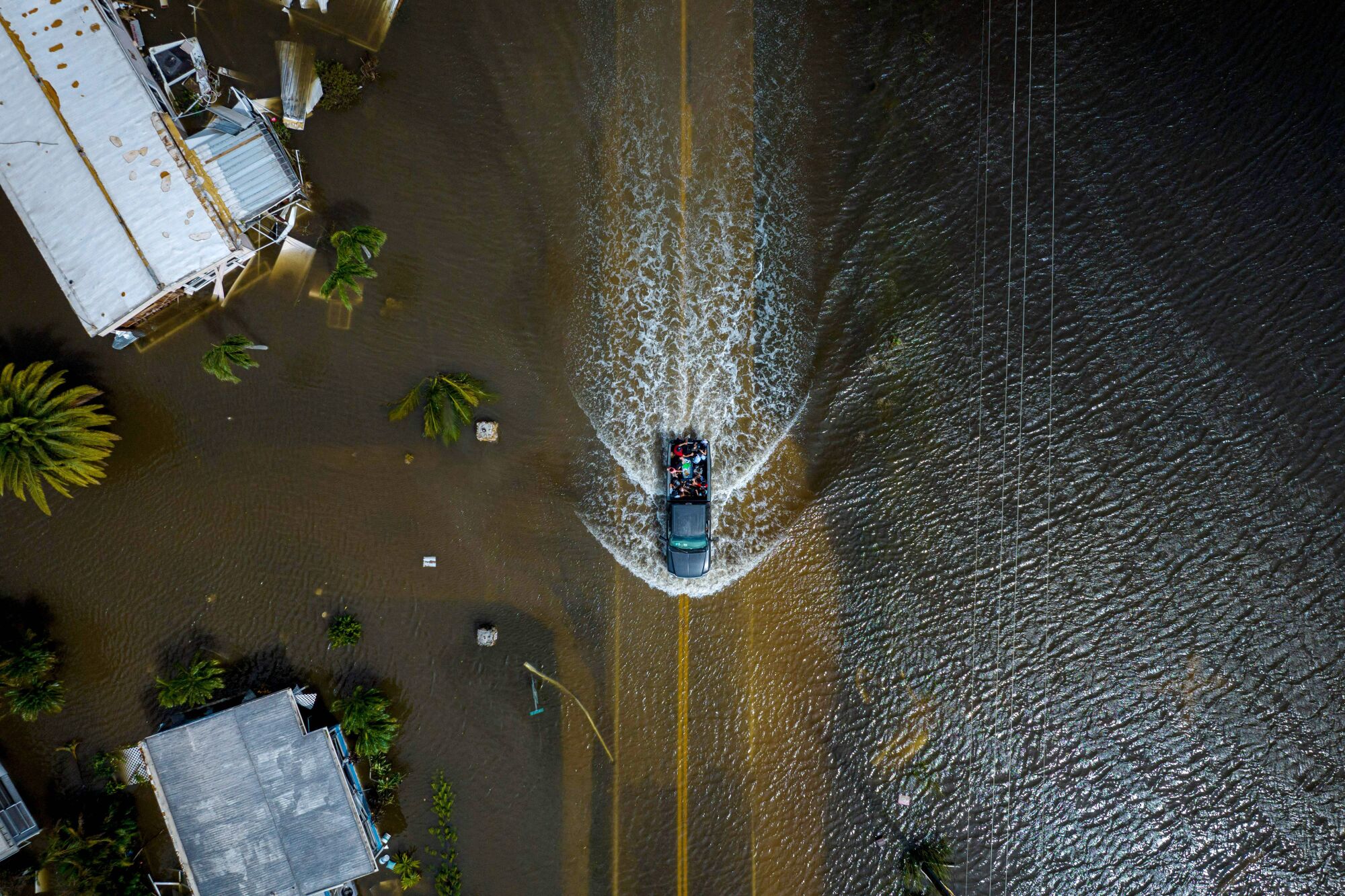 A car drives through a flooded neighborhood in the aftermath of Hurricane Ian in Fort Myers, Fla.