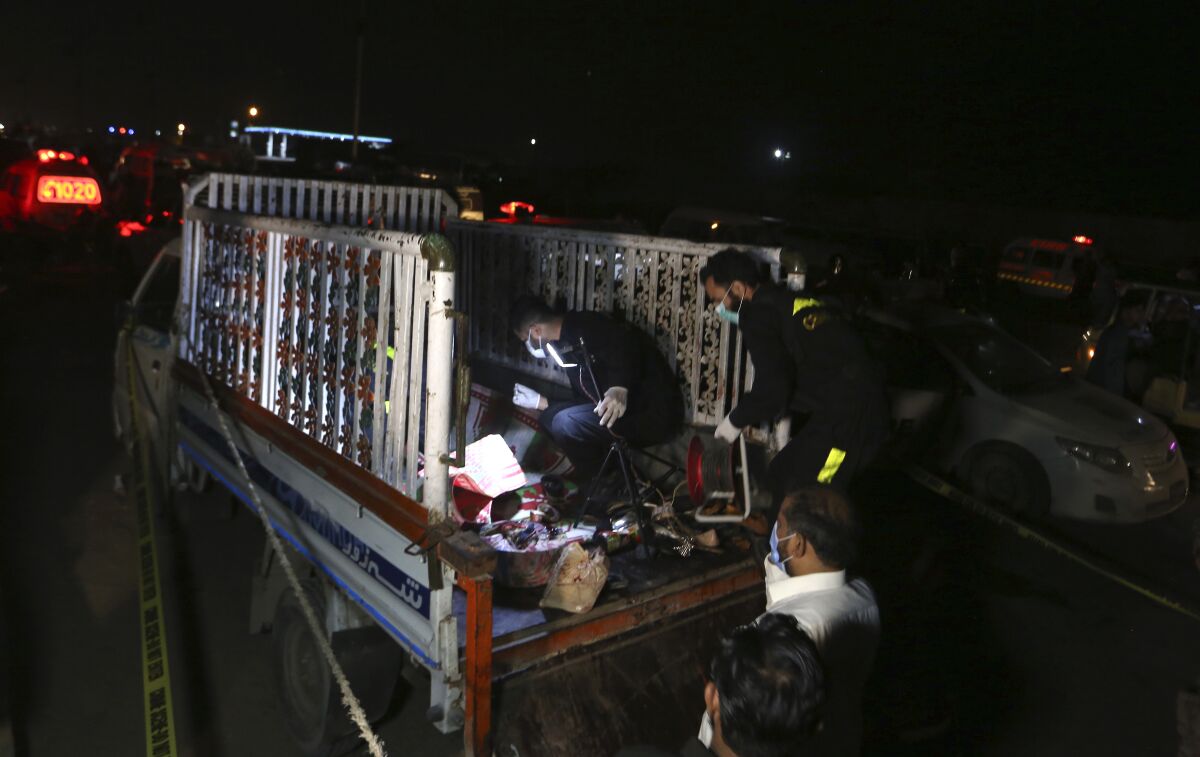 Pakistani investigators examine a truck at the site of an explosion, in Karachi, Pakistan, Saturday, Aug. 14, 2021. Attackers targeted a truck in the Pakistani port city of Karachi, killing multiple people and wounding others. An initial investigation suggests the attackers followed the truck and then threw hand grenades or some sort of improvised explosive devices at one side of the truck, police said. (AP Photo/Fareed Khan)
