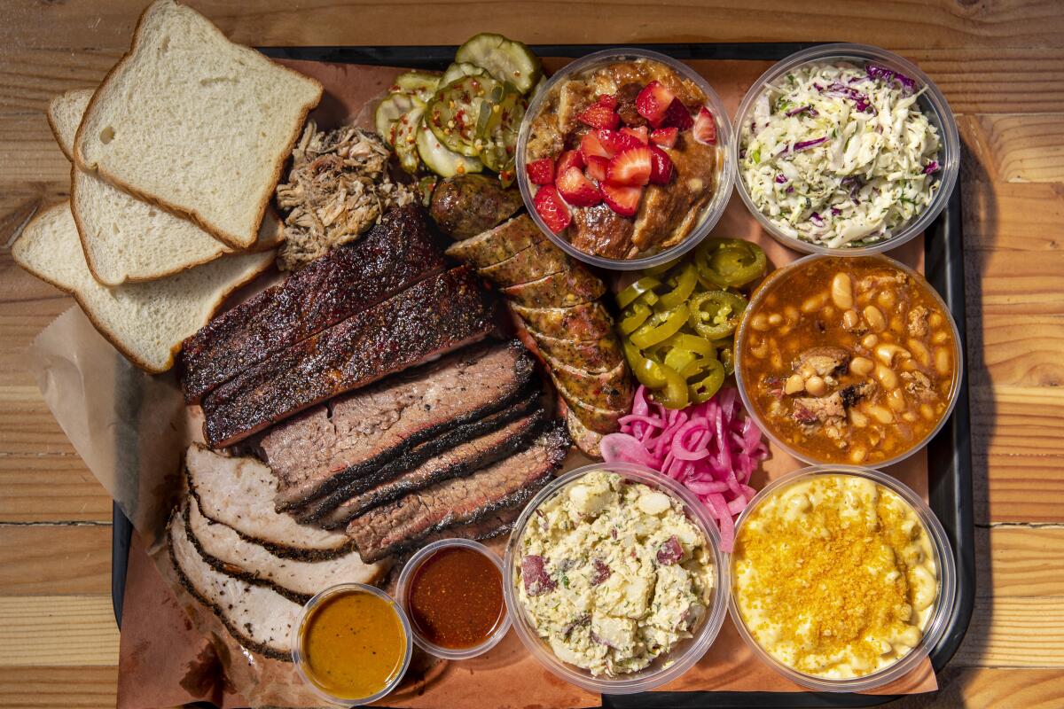 A platter of sliced meats surrounded by sides
