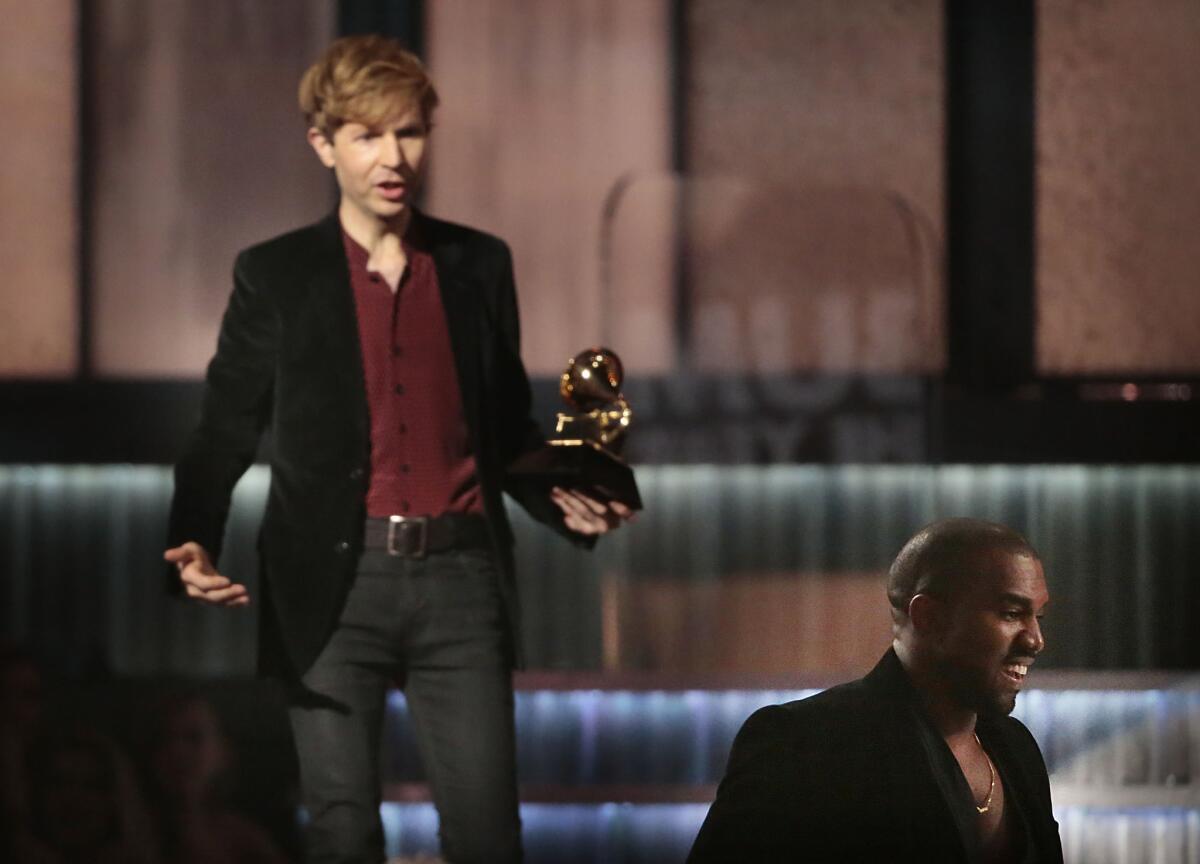 Kanye West , right, avoids contact with an inviting Beck after Beck won album of the year at the 57th Grammy Awards in Los Angeles on Feb. 8, 2015.