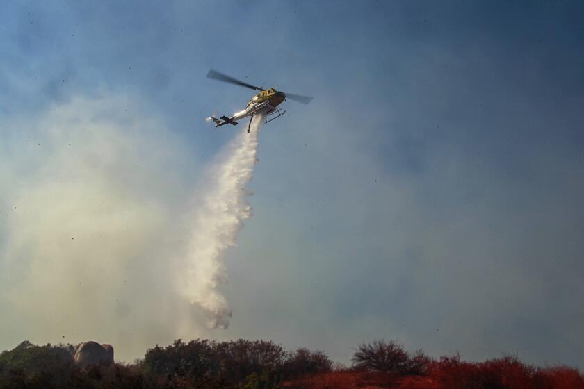 A Fire Department helicopter makes a water drop on a blaze east of Cole Grade Road at Miller Lane on October 25, 2019 in Valley Center, California.