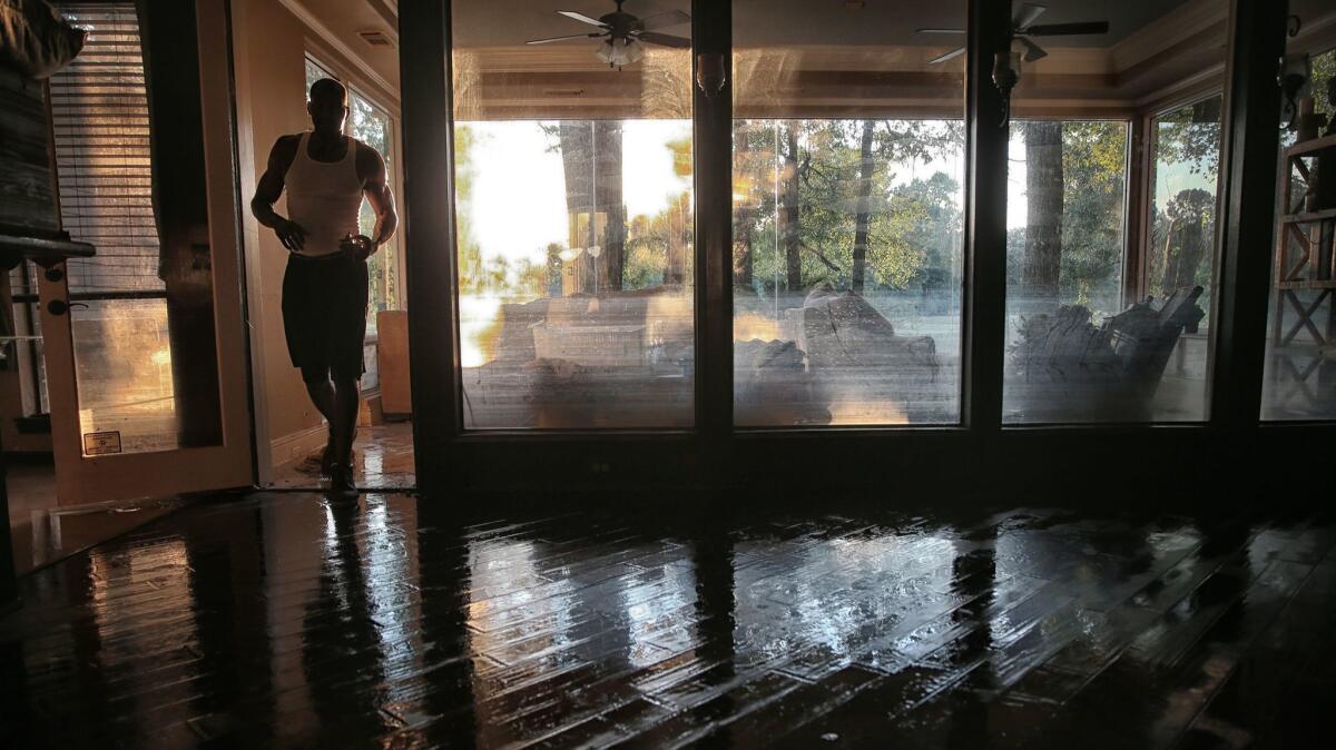 Charles Lewis walks into his living room next to windows that show how high the water came.