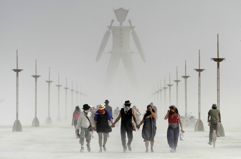 FILE - In this Aug. 29, 2014, file photo, Burning Man participants walk through dust at the annual Burning Man event on the Black Rock Desert of Gerlach, Nev. The cancellation of Burning Man for the second year is drawing mixed reaction in northern Nevada, where some businesses and tourism officials say they'll miss the economic boost from festival-goers but health officials are glad they won't contribute to increasing the risk of spreading COVID-19. (Andy Barron/The Reno Gazette-Journal via AP, File)