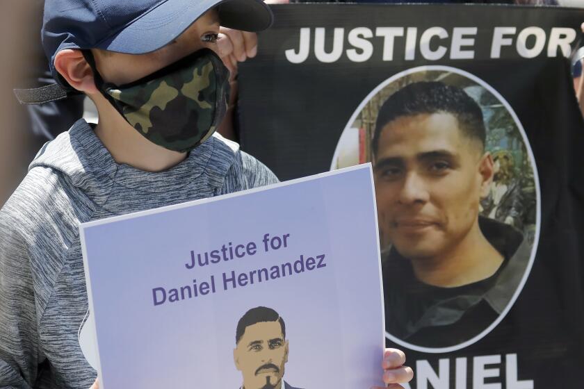 LOS ANGELES, CALIF. - JUNE 26, 2020. Matthew Hernandez, 8, holds a sign with a picture of his uncle, Daniel Hernandez, during a press conference at the L.A. County Hall of Justice on Friday, June 26, 2020. Daniel Hernandez was fatally shot by members of the LAPD in South Los Angeles. The Latino Coialition of Los Angeles is calling for complete and transparent investigations iof officers who have shot and killed Latinos and Blacks. (Luis Sinco/Los Angeles Times)