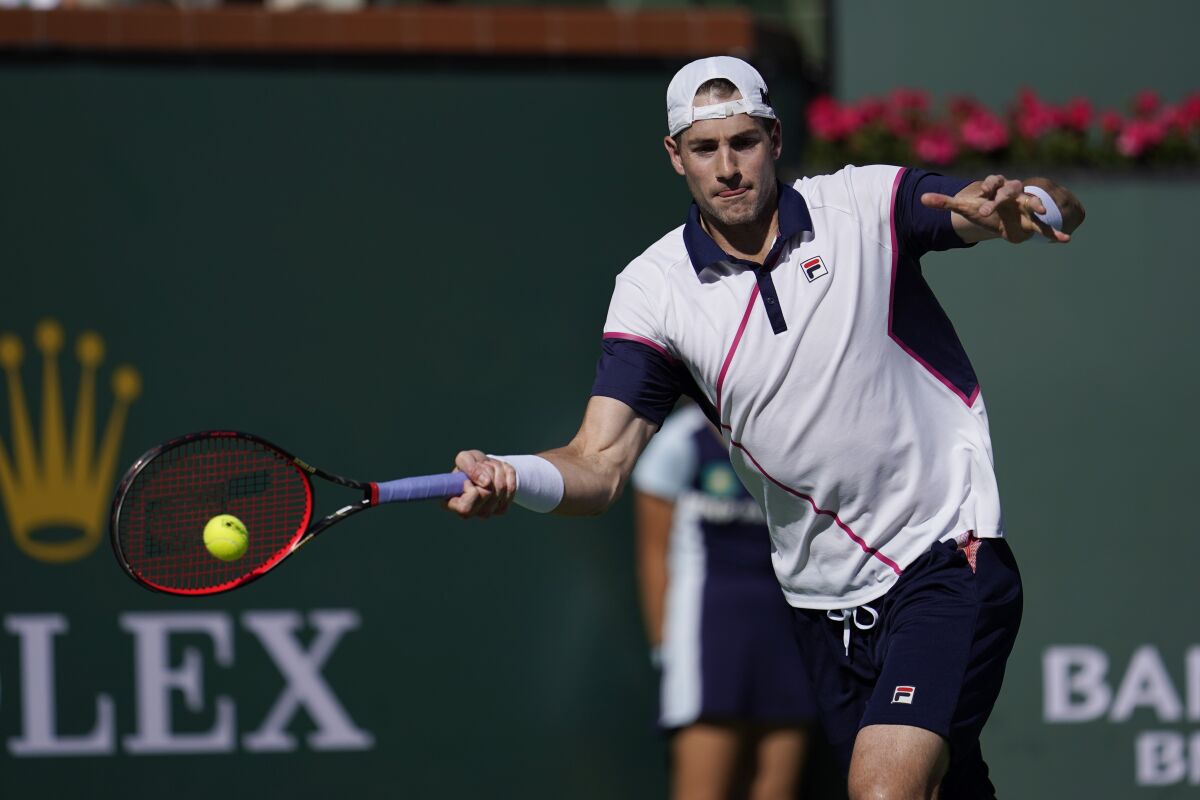 FILE - John Isner returns to Diego Schwartzman, of Argentina, at the BNP Paribas Open tennis tournament Tuesday, March 15, 2022, in Indian Wells, Calif. At 37, John Isner is just happy to be back on tour in Europe with his wife and three kids. No longer dreaming of a Grand Slam title, he’s trying to make the back end of his tennis career not seem “like such a job.” Yet there’s serious business coming up Wednesday, May 11 with a second-round matchup against 10-time champion Rafael Nadal in the second round of the Italian Open. (AP Photo/Marcio Jose Sanchez, file)