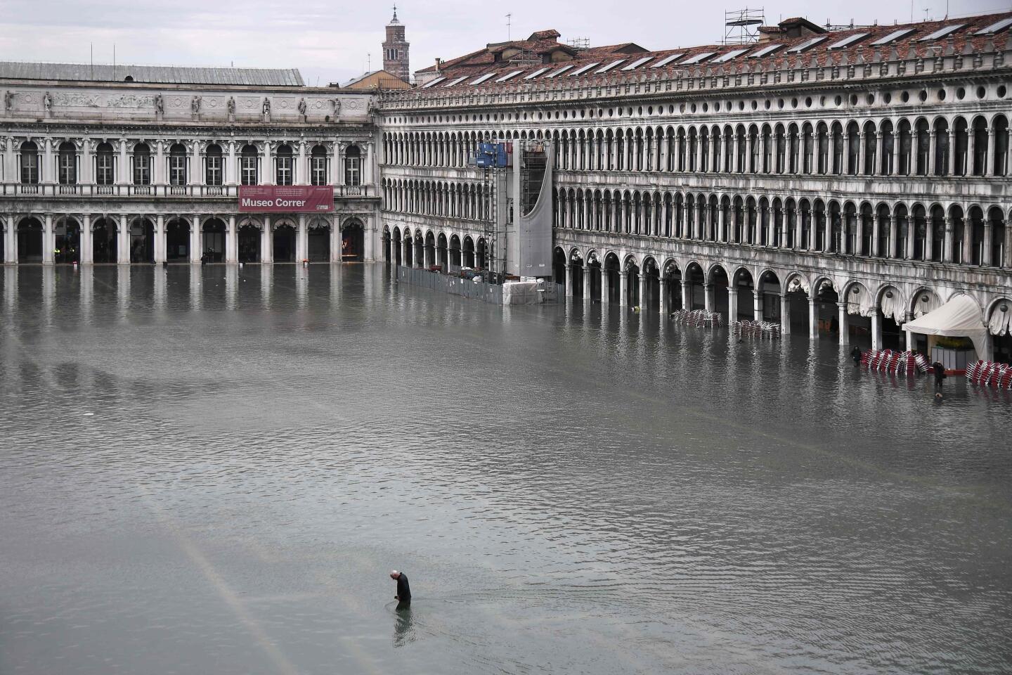 A man crossing the flooded St. Mark's Square.