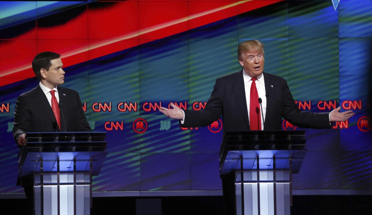 Sen. Marco Rubio listens as Donald Trump speaks and gestures during a debate.