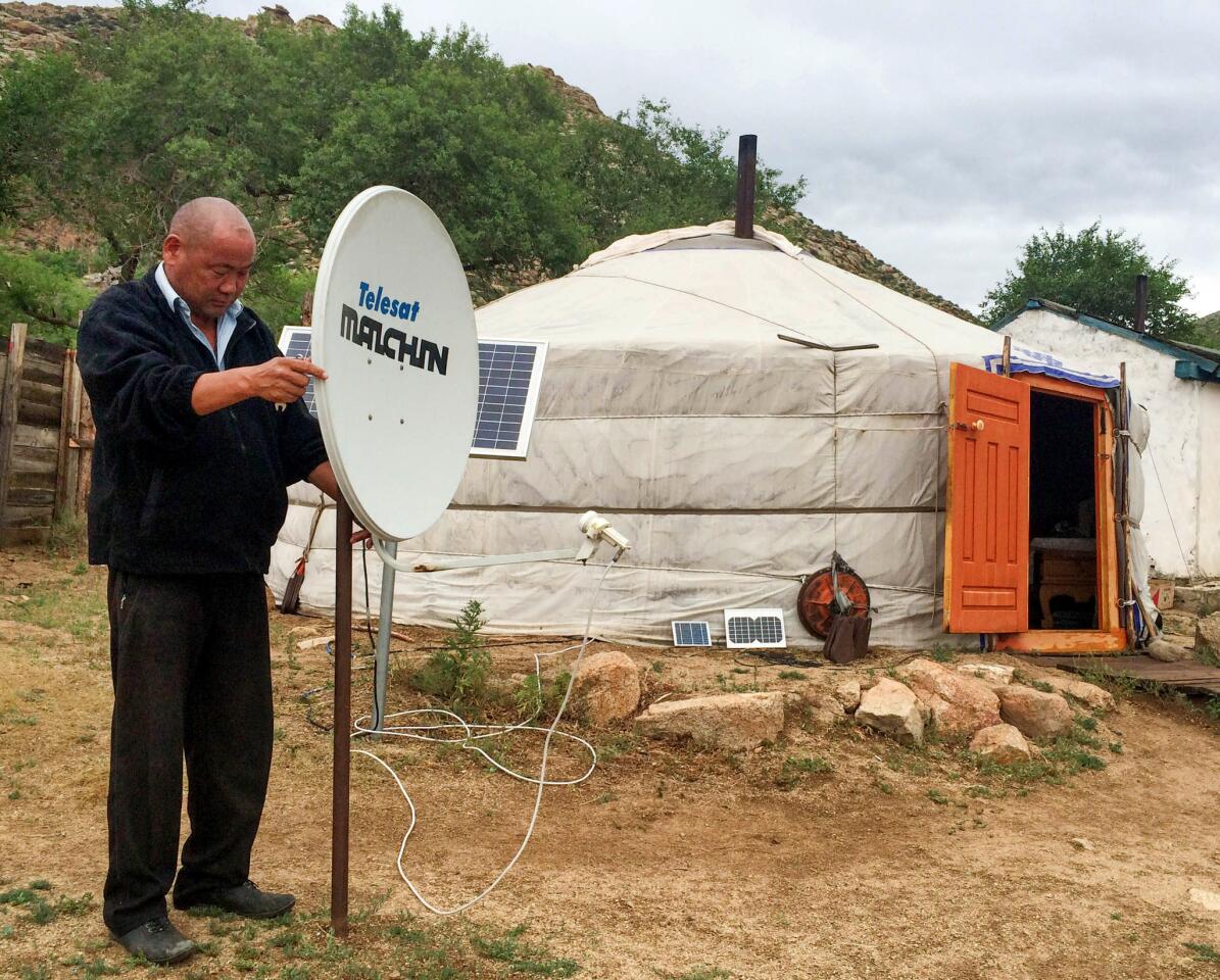 Tsagaana Davaa adjusts the solar-powered satellite dish outside his yurt in a remote part of Mongolia. He gets more than 60 stations, offering everything from “Breaking Bad” to Hollywood blockbusters.