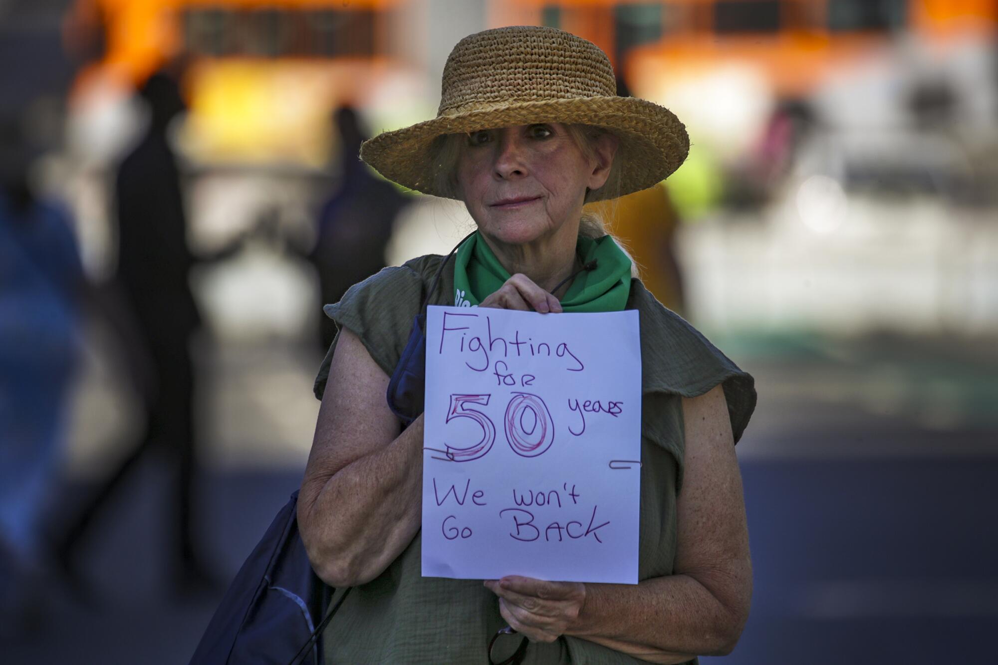 Jean English, 67, holds a piece of paper that says, "Fighting for 50 years. We won't go back." 